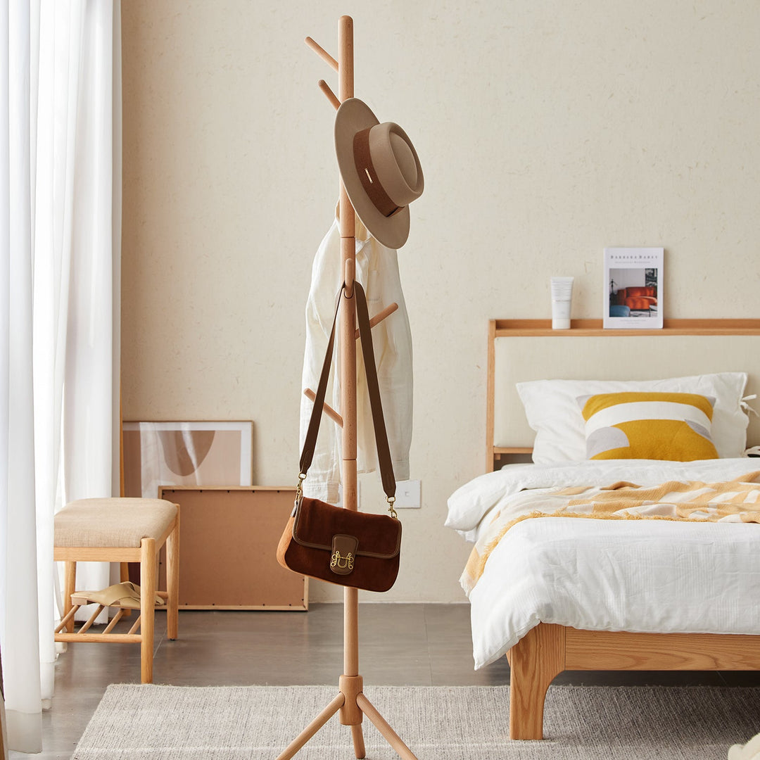 Scandinavian-style wooden clothes hanger with minimalist design, featuring multiple hooks for organizing garments and accessories in a serene bedroom setting.