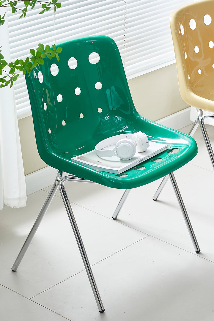 Green plastic chair and a plant in a room with white blinds. Featured in the Loft Home plastic chairs collection.