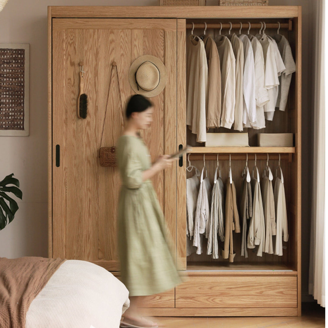 Modern wooden wardrobe with sliding doors, featuring ample hanging space and a minimalist design, ideal for organizing clothes in compact bedrooms.