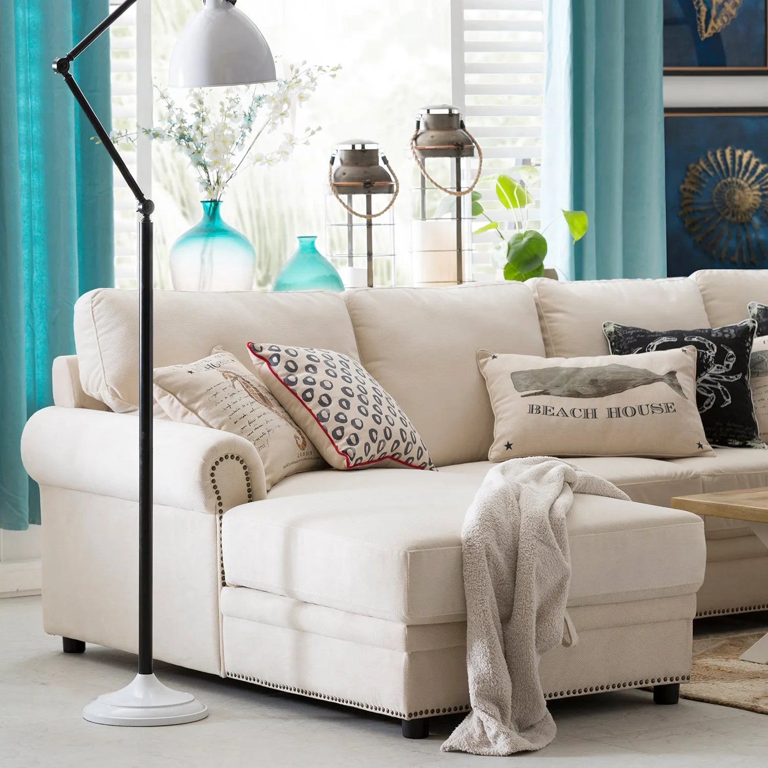 Cover picture for Loft Home's Sofas by Material collection: cozy living room with a cream sectional sofa, decorative pillows, and a floor lamp, featuring a mix of textures and materials.