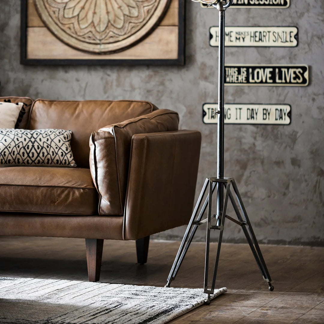 Cover picture for Loft Home's Sofas by Size collection: stylish living room with a brown leather sofa, decorative pillows, and a modern floor lamp.