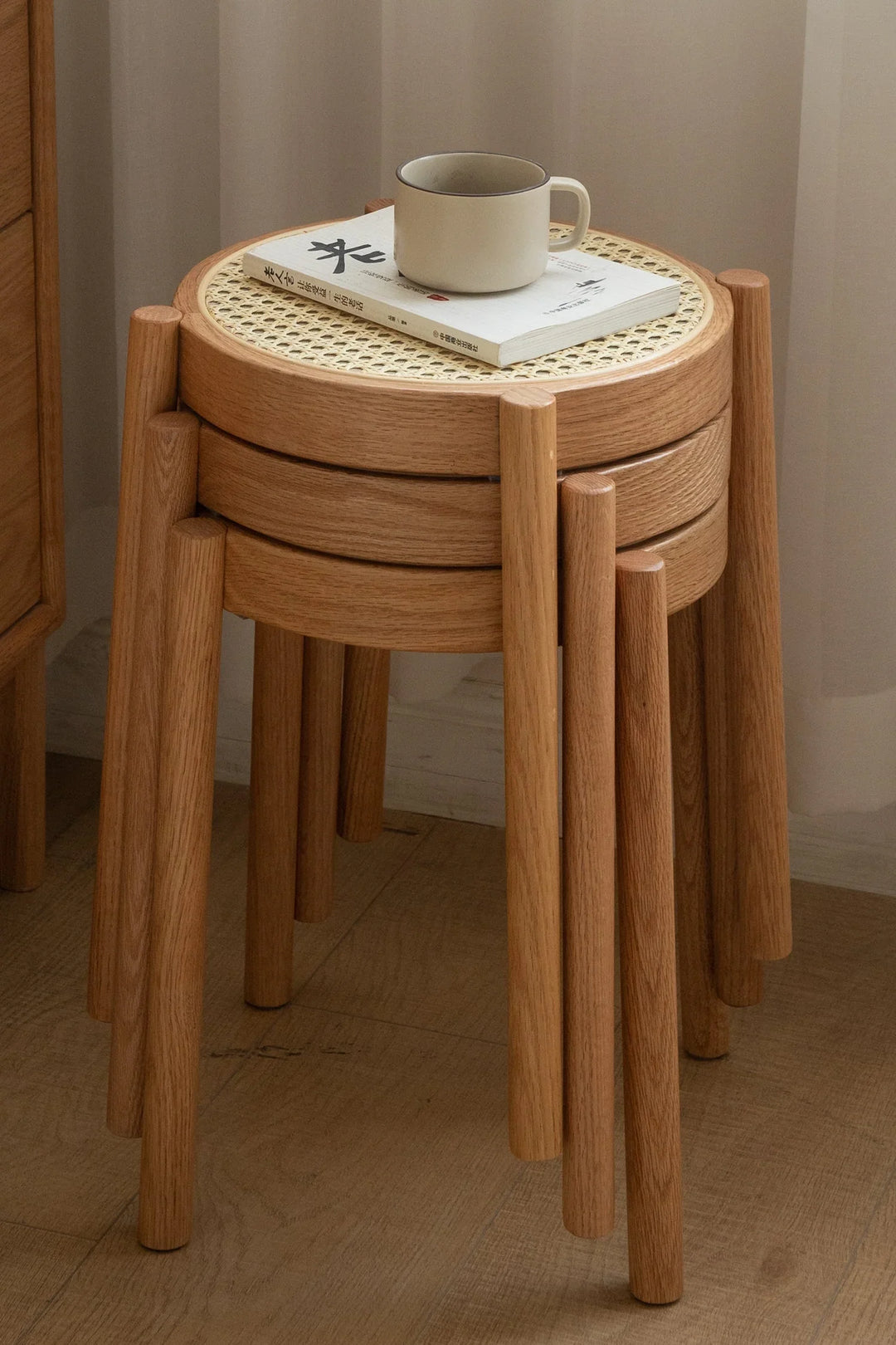 Stackable wooden stools with woven top on a wooden floor. Loft Home stools collection cover picture.