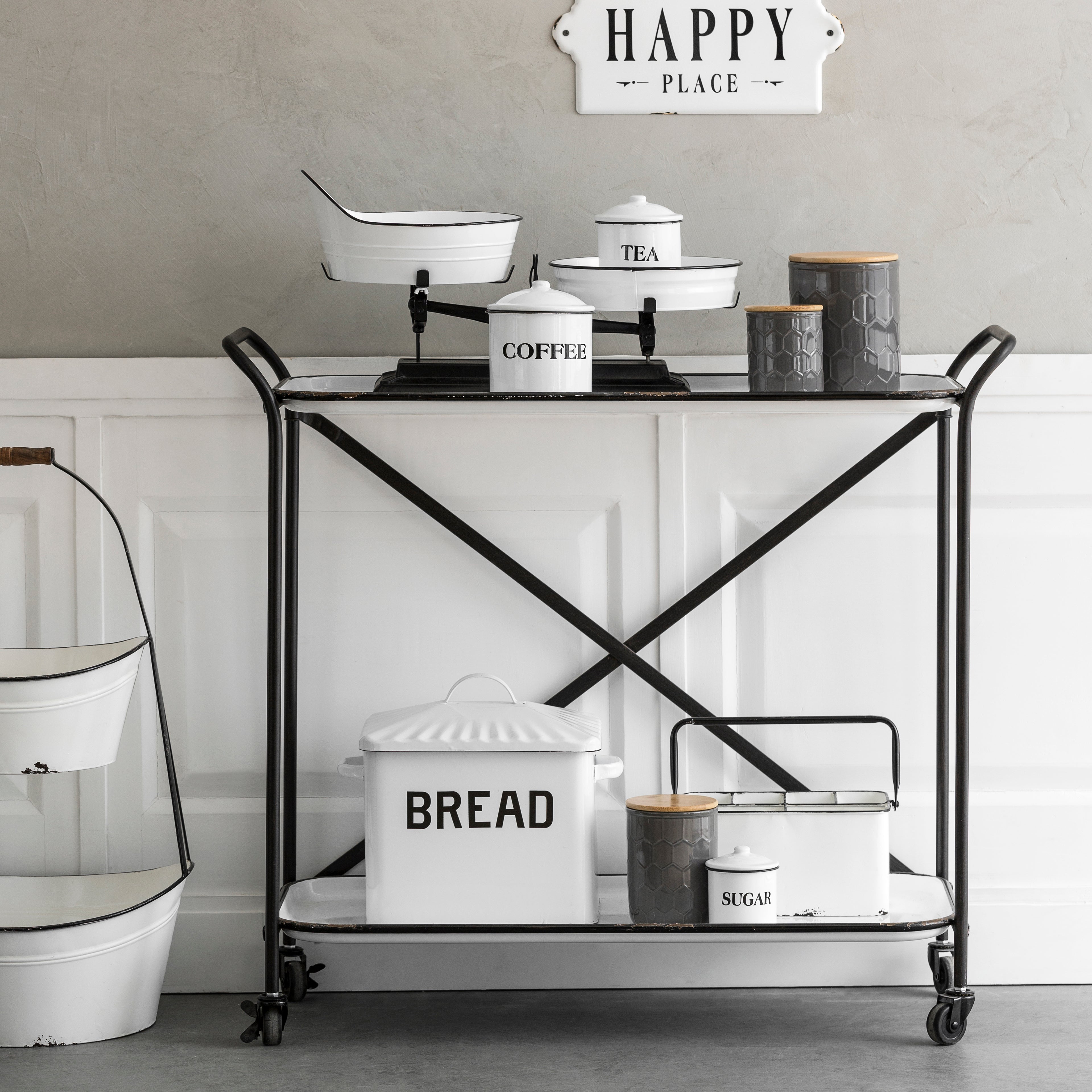 Loft Home industrial-style storage cart with metal frame and white shelves, adorned with vintage-inspired bread and coffee canisters, perfect for functional and stylish kitchen organization.