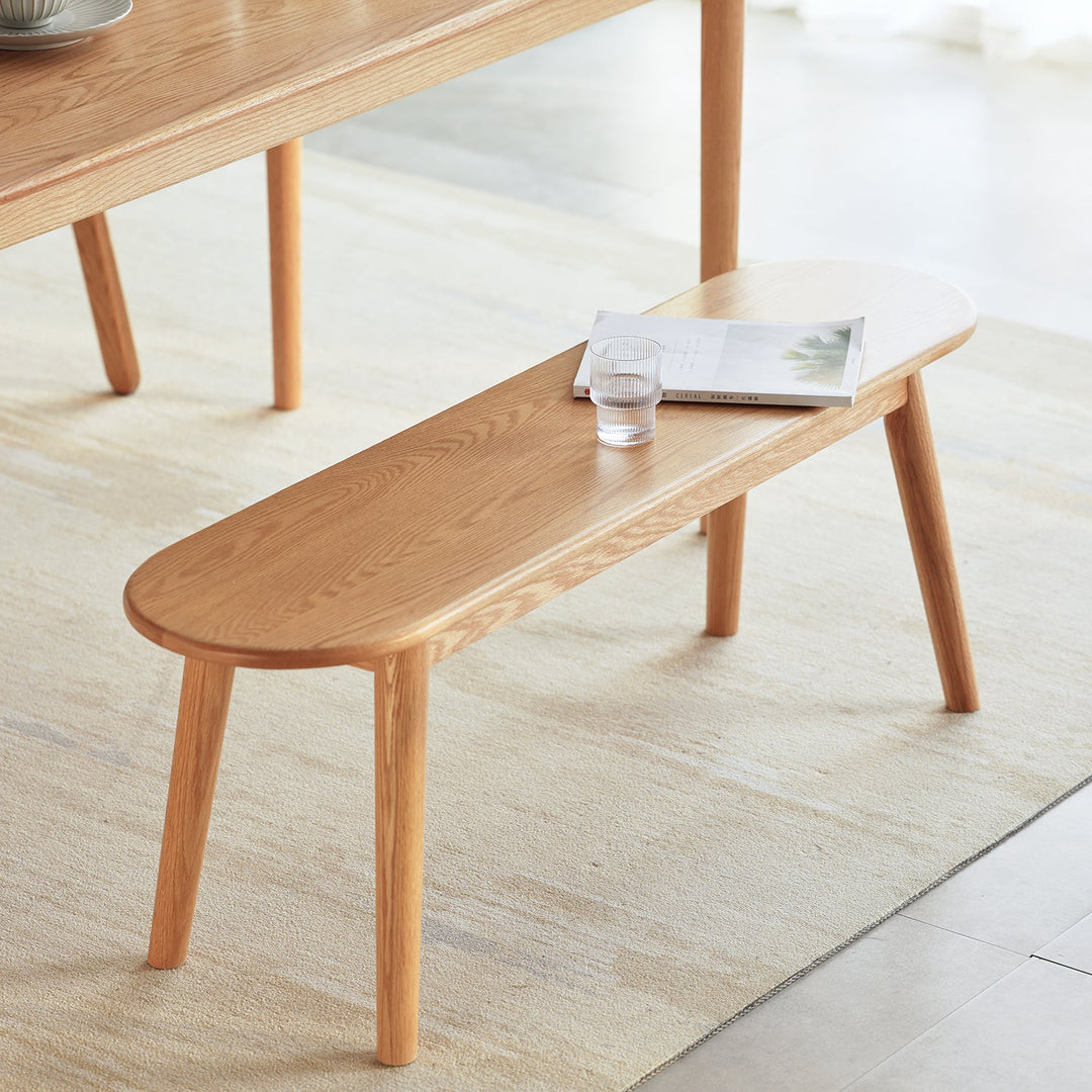 Minimalist wooden bench crafted from solid oak, featuring a sleek oval seat and tapered legs, perfect for dining or entryway spaces.