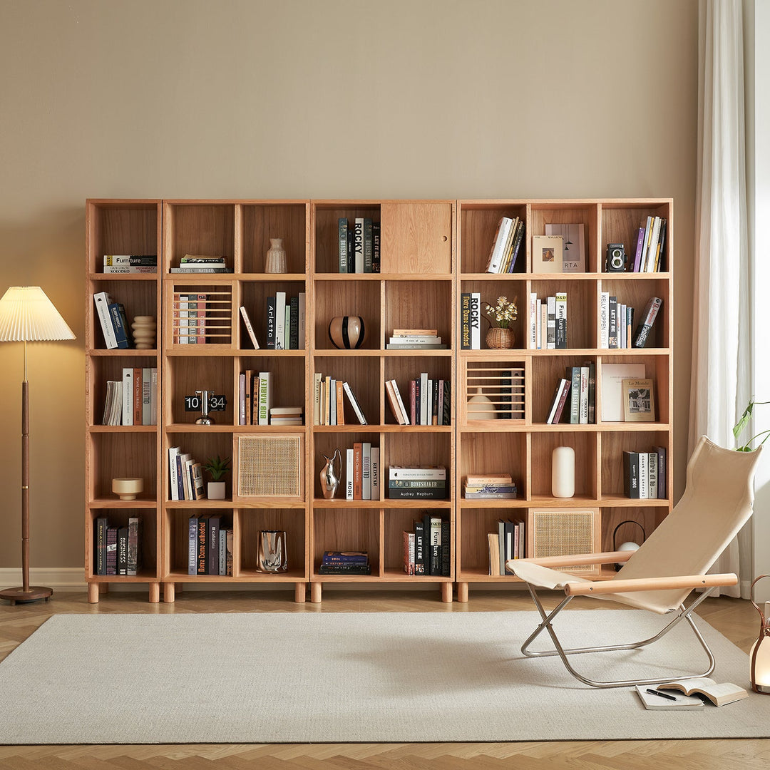 Spacious wooden bookshelf with modular compartments, showcasing books, decor items, and rattan-accented panels, perfect for modern or minimalist living spaces.