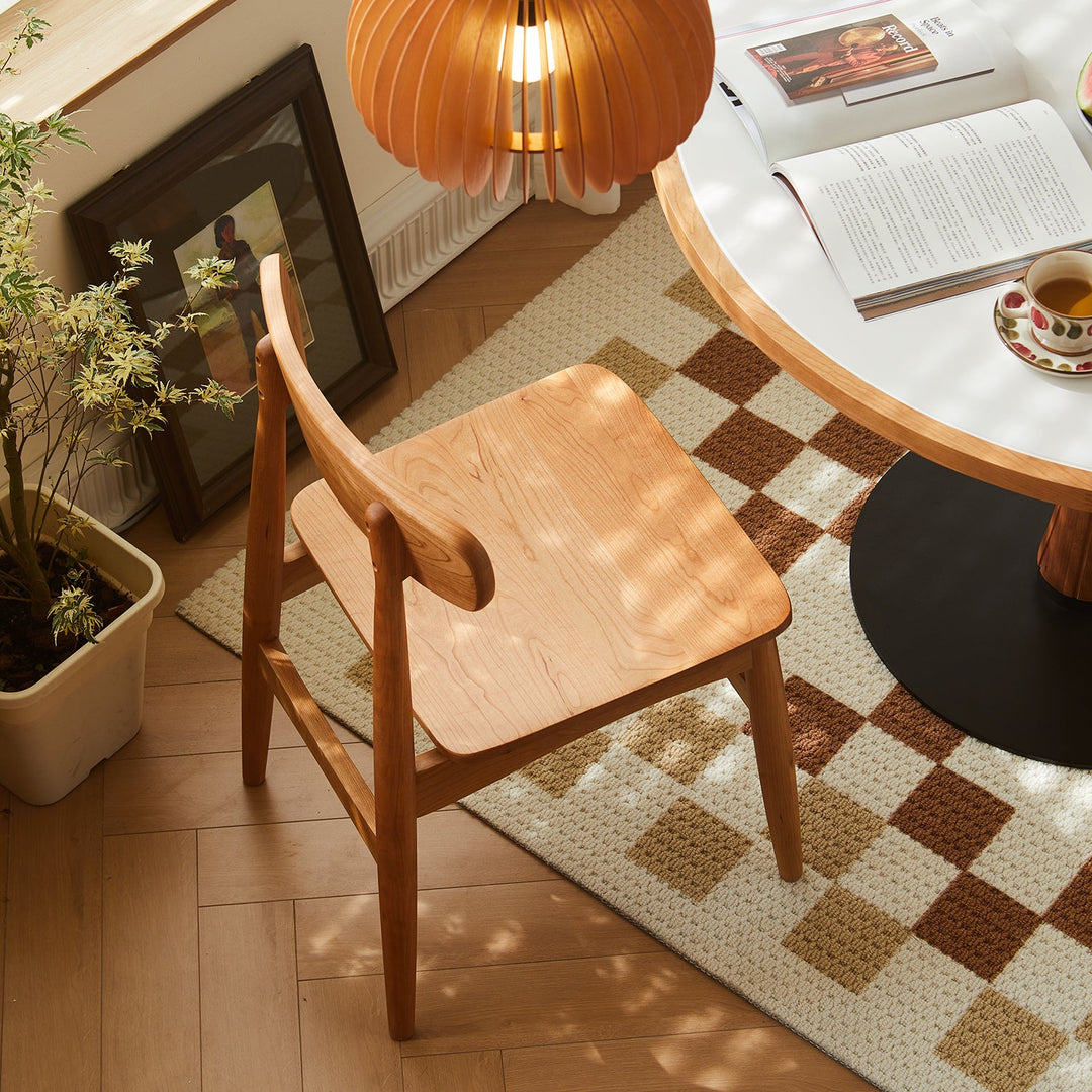 Elegant wooden dining chair with a natural finish, showcasing a minimalist design, complementing a cozy dining space with warm tones and modern decor.