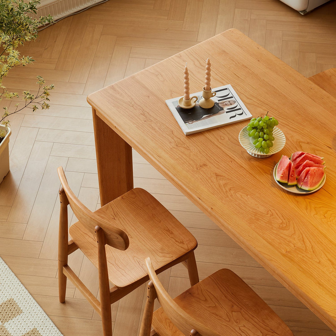 Loft Home wooden dining table collection, showcasing a solid wood dining table and matching chairs, styled with fresh fruits and candles, creating a cozy and inviting dining space.