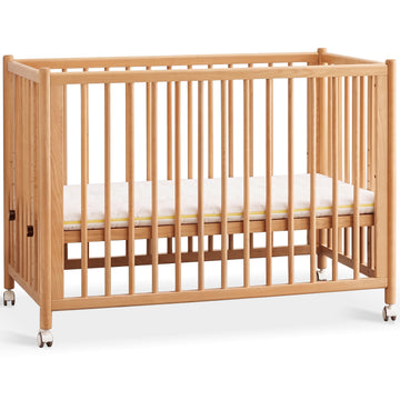 Scandinavian beech wood bed side baby crib with wheels ember in white background.