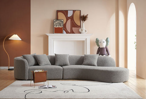 Modern living room with a grey curved sectional sofa and contemporary decor. Explore the sofa collection at Loft Home Furniture.