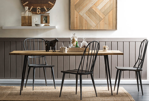 Rustic dining room featuring a wooden dining table with black metal chairs, complemented by farmhouse decor and wooden wall art, linking to Loft Home's dining table collection.