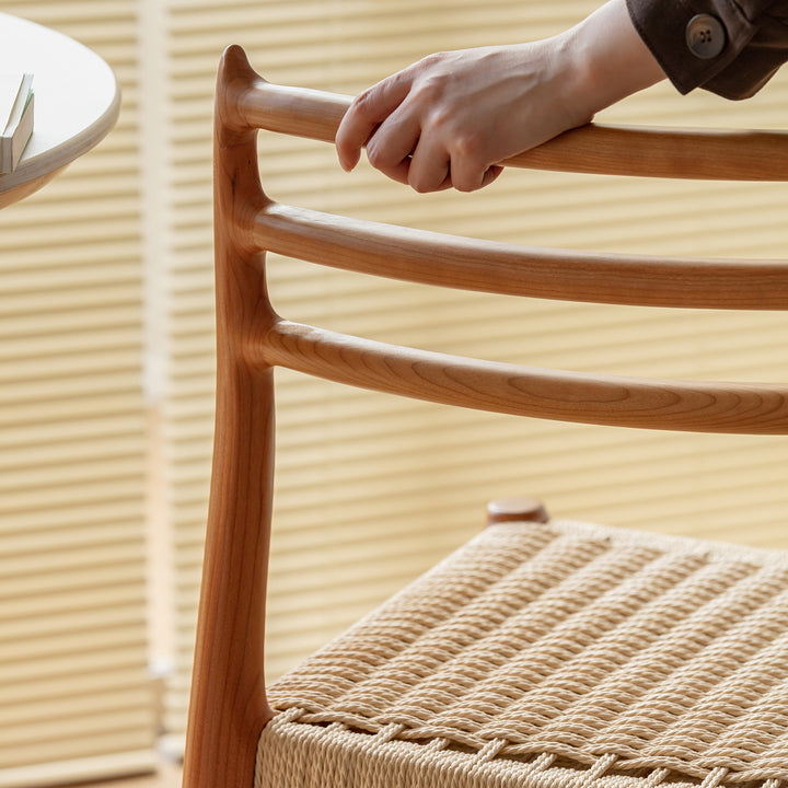 Scandinavian cherry wood woven rope dining chair autumn in still life.