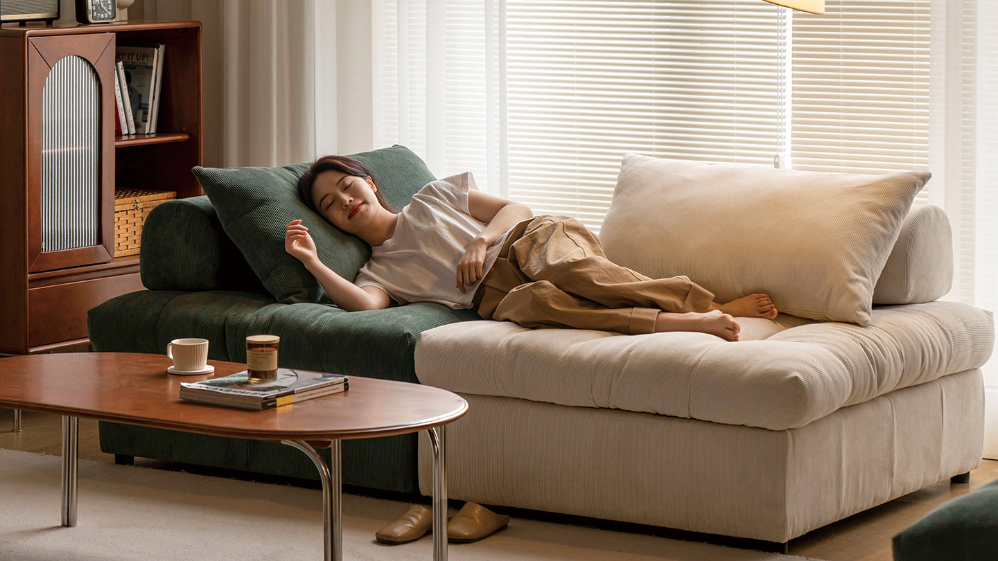 Woman relaxing on a plush sectional sofa in a cozy living room, featuring warm tones and modern furniture, perfect for unwinding at home.