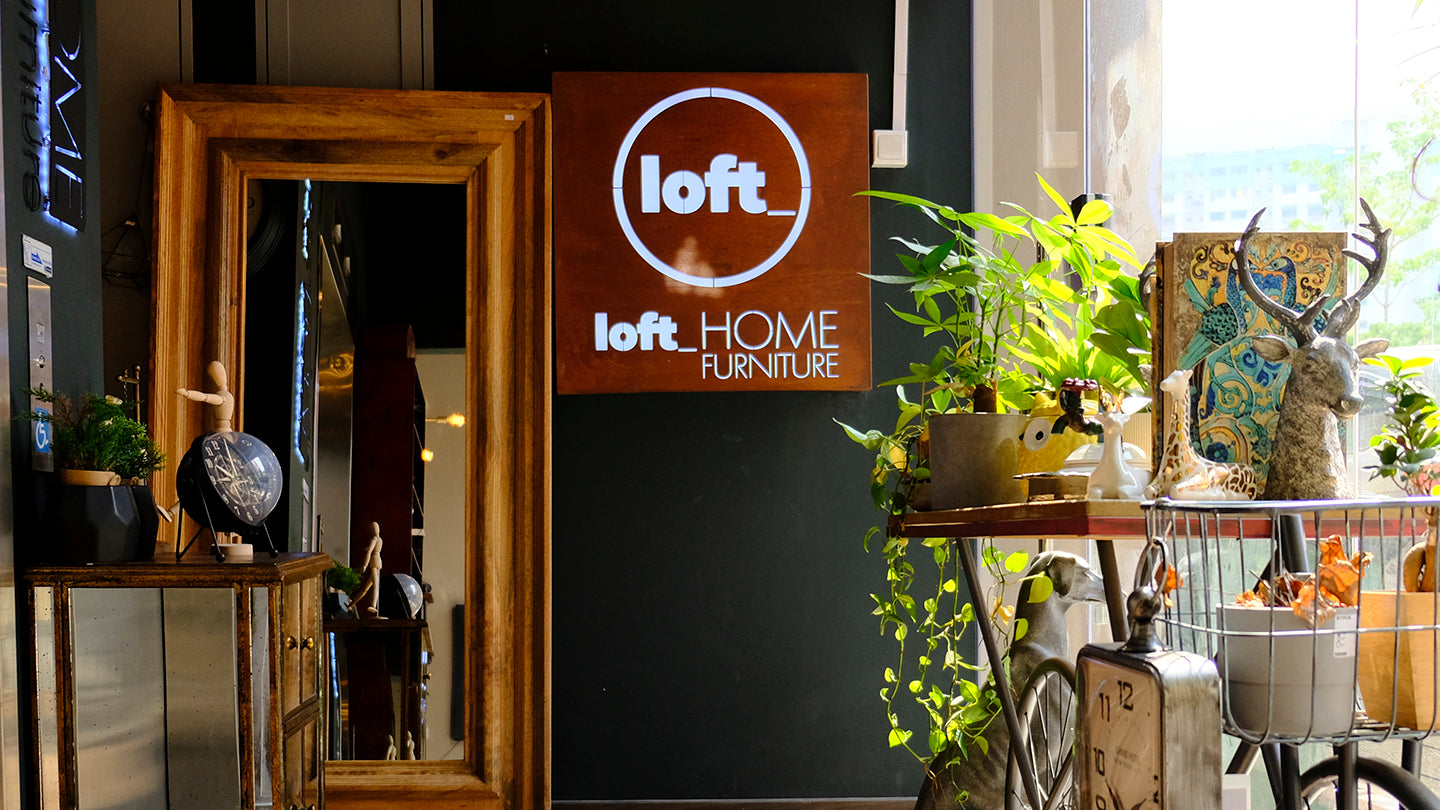 Interior setting with 'loft' home furniture sign, plants, and decorative items.