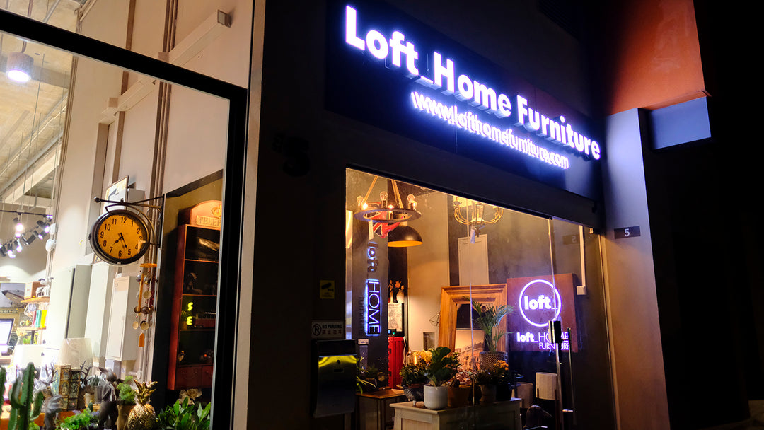 Exterior view of Loft Home Furniture showroom with a glowing storefront sign and a cozy interior, inviting customers to visit.