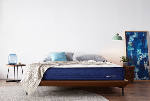 Modern bedroom featuring a comfortable Loft Home mattress with blue upholstery, cozy bedding, and minimalist decor, linking to Loft Home's mattress collection.