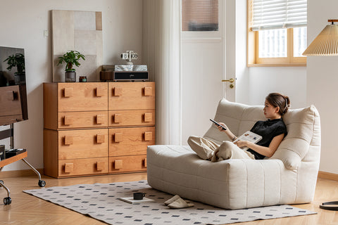 Woman reading a book on a white armchair in a modern living room.