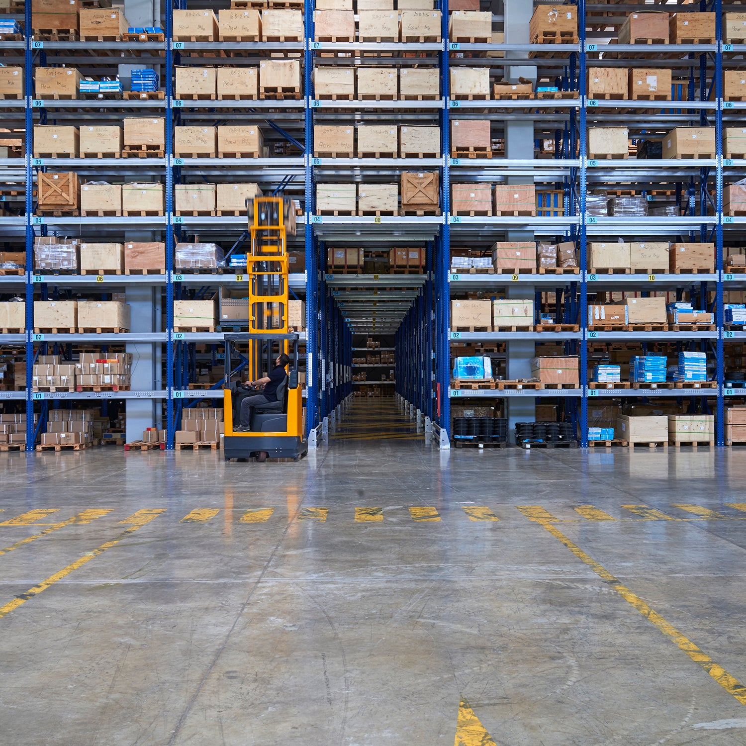 Warehouse interior with shelves stocked with boxes and a forklift operator.