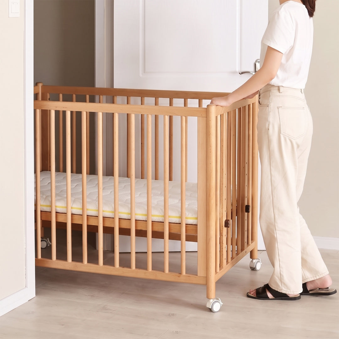 Scandinavian beech wood bed side baby crib with wheels ember color swatches.