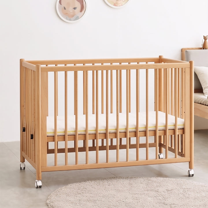 Scandinavian beech wood bed side baby crib with wheels ember with context.