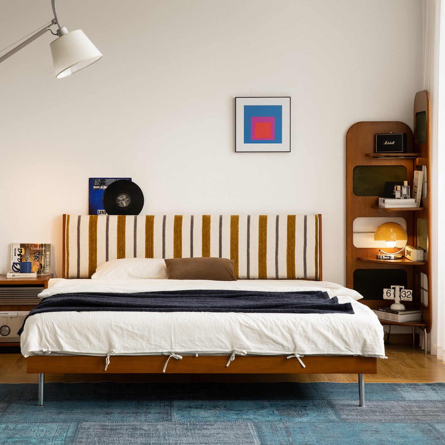 Striped fabric headboard bed with wooden frame and modern shelving, styled with warm lighting for a cozy Loft Home bedroom interior.