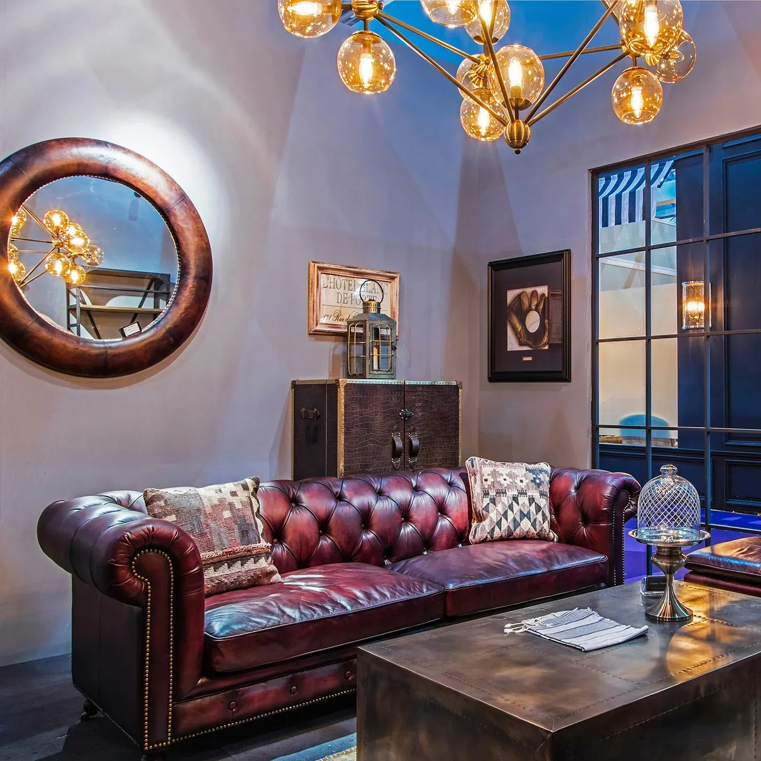 Vintage-inspired living room with a luxurious Chesterfield sofa, industrial coffee table, decorative mirror, and unique lighting, creating an elegant ambiance.