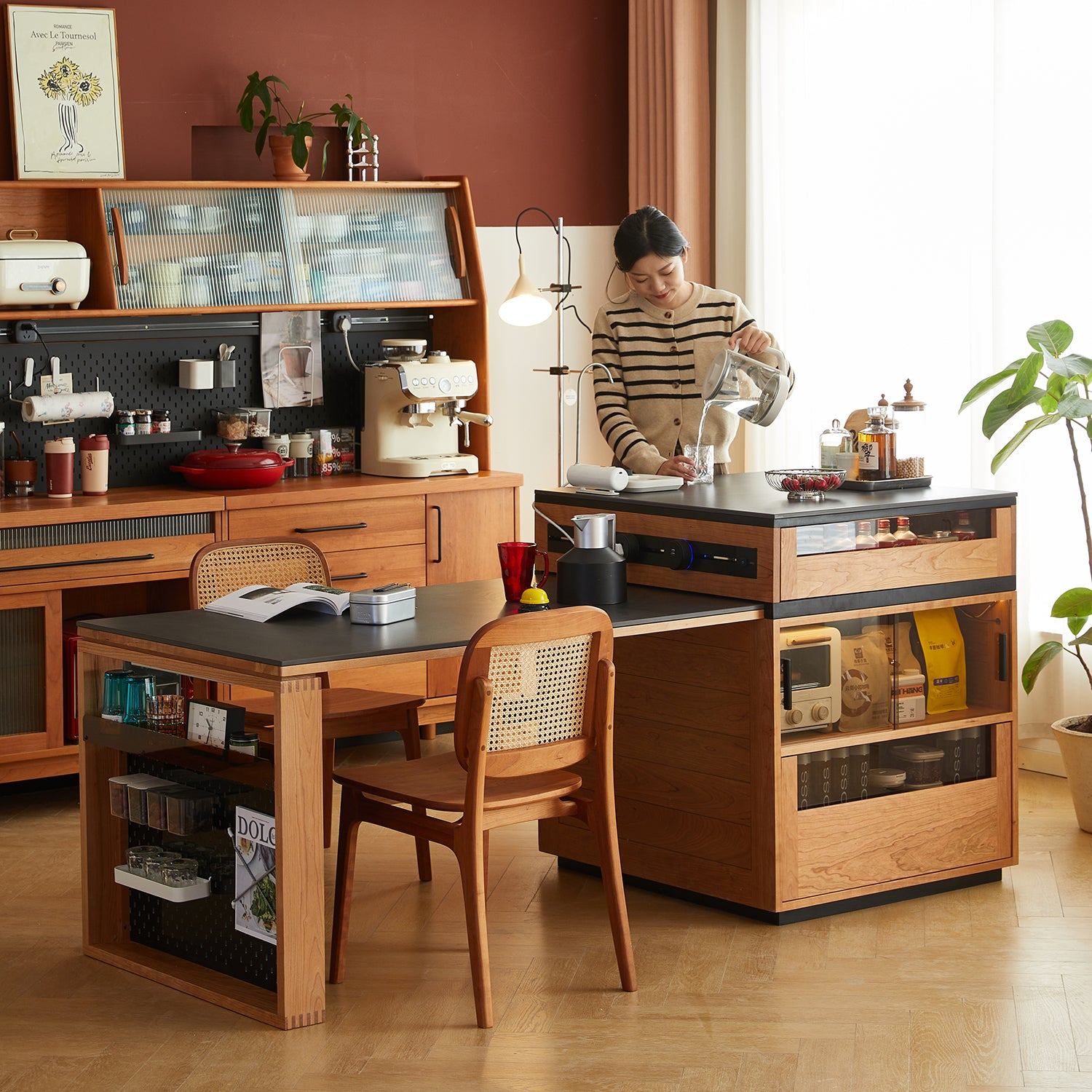 Cozy kitchen setup with wooden cabinets, dining table, coffee station, and a woman pouring water, creating a warm and inviting atmosphere.