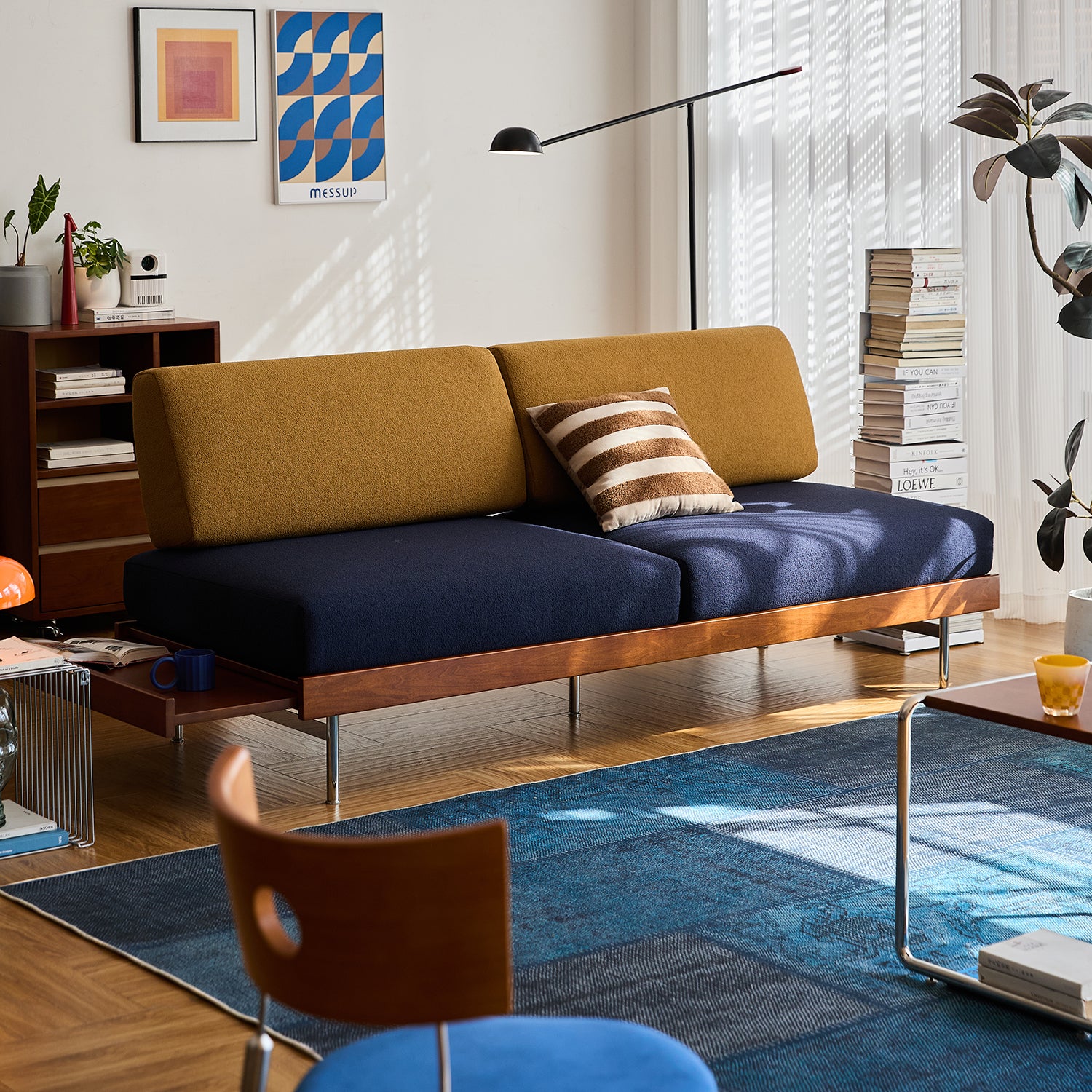 Vintage-style 3-seater sofa in mustard and navy bouclé fabric, framed in rich wood with sleek chrome legs, adding bold retro charm to a sunlit living room.